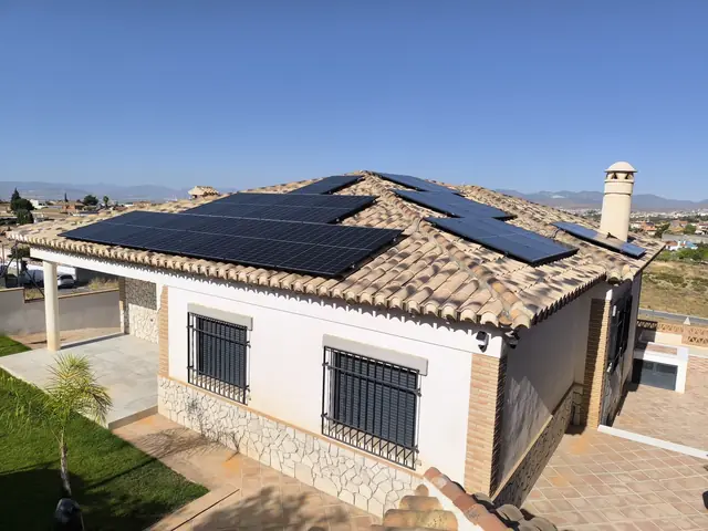 Casa unifamiliar con tejado de teja y paneles solares negros en varios faldones