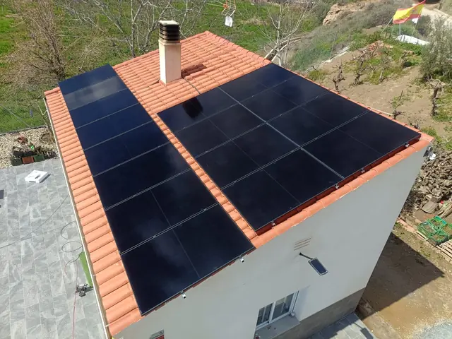 Vista aérea de un tejado de teja roja con paneles solares negros